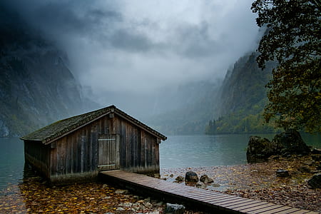 photo of brown wooden house on top of body of water during cloudy sky thumbnail