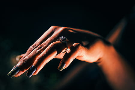 tilt-shift lens photography of woman's hand with black-and-green floral accent manicure thumbnail