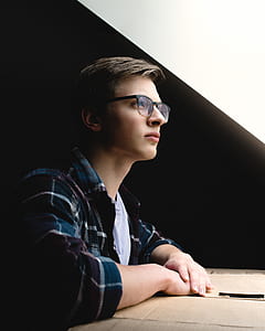 man wearing eyeglasses and green and maroon plaid dress shirt sitting thumbnail