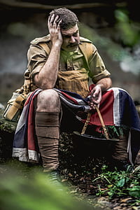man sitting on rock holding helmet holding his head during daytime thumbnail