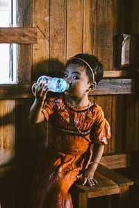 girl drinking bottle of water while sitting on stool thumbnail