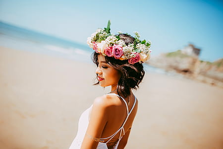 woman in white spaghetti strap top standing on seashore during daytime shallow focus photography thumbnail