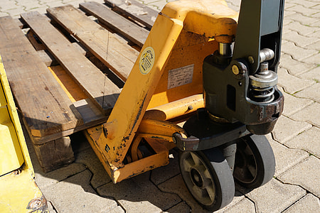 yellow and black pallet truck with wooden pallet on concrete pathway during daytime thumbnail