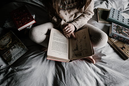 person reading book while sitting on bed thumbnail