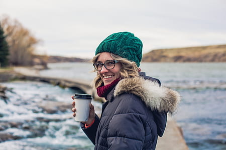 woman wearing green knit hat while holding white disposable cup thumbnail