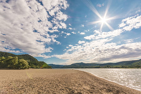 sand and body of water under blue sky during daytime thumbnail