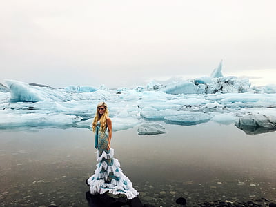 woman wearing white and green dress standing beside sea covered with ice blocks thumbnail