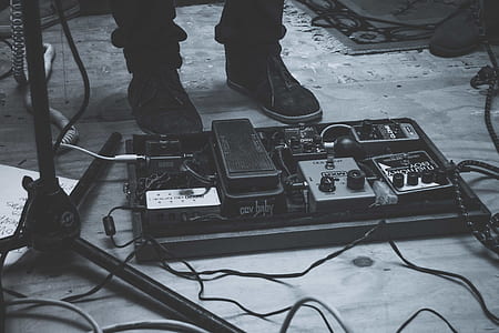 person standing beside guitar controller pad in grayscale photography thumbnail