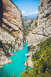Body of Water Surrounded by Mountain Under Blue Sky at Daytime thumbnail
