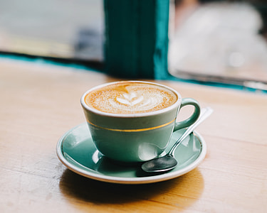 grey ceramic teacup with latte and saucer on brown wooden table thumbnail