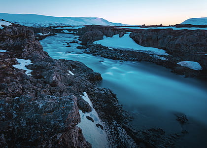 flowing body of water between cliffs and rocks during daytime thumbnail