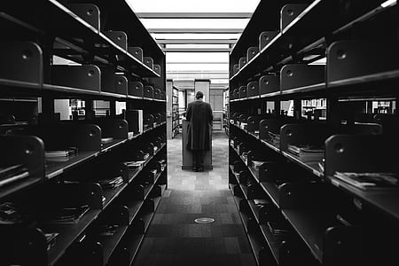 grayscale photo of woman standing near gray shelf thumbnail