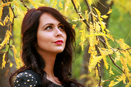 woman wearing a black scoop neck top standing under a tree thumbnail
