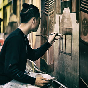 Man In Black Sweatshirt Holding Black Paint Brush Painting the Wall thumbnail