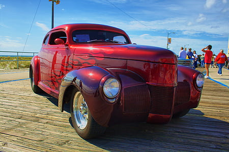 vintage red vehicle parked near walking people thumbnail