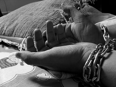 greyscale photo of human hands tied with grey chain thumbnail