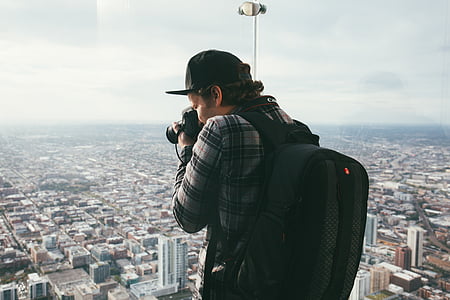 man taking photo of buildings using black DSLR camera during daytime thumbnail