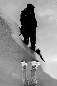grayscale photo of man standing near water puddle thumbnail