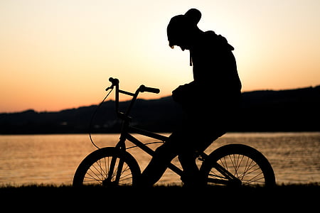 silhouette photography of man riding BMX bicycle near body of water during golden hour thumbnail