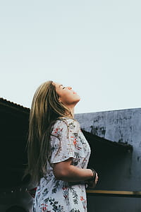 woman wearing floral shirt head facing upward with closed eyes while looking up during daytime thumbnail