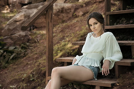Woman Wearing White Long Sleeve Shirt Sitting on Brown Wooden Stairs thumbnail