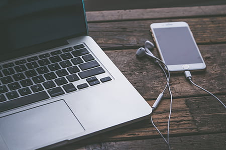 iPhone displaying black screen beside MacBook on table thumbnail