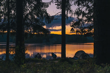 group of people camping in forest during sunset thumbnail