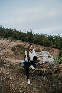 woman sitting on brown stone looking sideway thumbnail