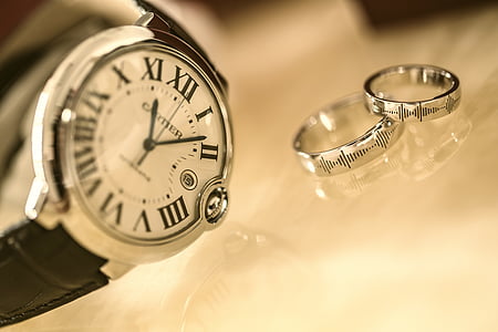 round silver-colored analog watch beside two silver-colored rings thumbnail