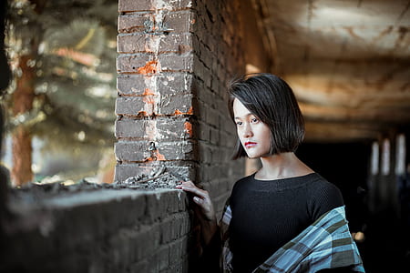 black-haired woman beside bricked wall thumbnail