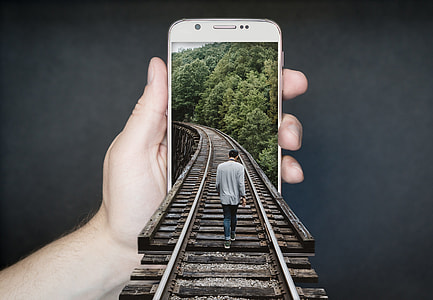 man walking on train rail through person holding white smartphone optical illusion artwork thumbnail