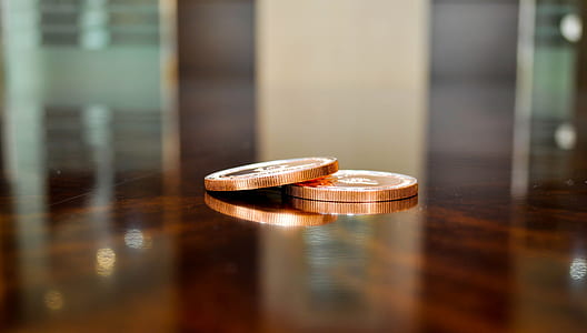 two gold-colored coins on brown surface thumbnail