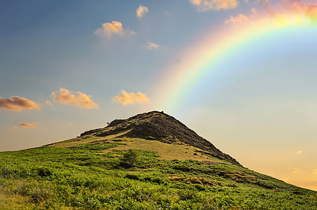 green and brown mountain with rainbow at daytime thumbnail