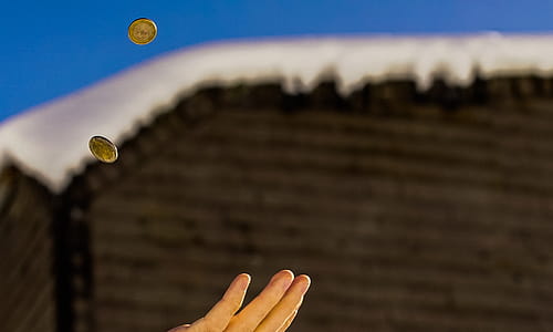 Shallow Focus Photography of Person Catching Two Gold-colored Coins thumbnail
