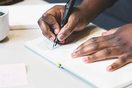 person drawing on paper with black pen thumbnail