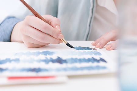 person holding brown paintbrush while paint thumbnail
