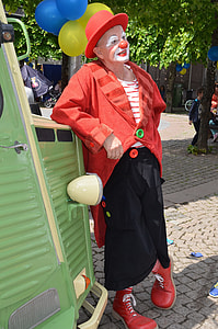 clown leaning on green plastic wall outside during daytime thumbnail
