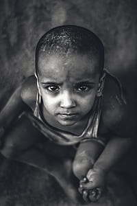 boy wearing tank top sitting on ground looking up thumbnail