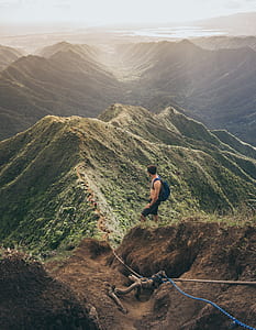 man standing on hill facing valley on a distant thumbnail