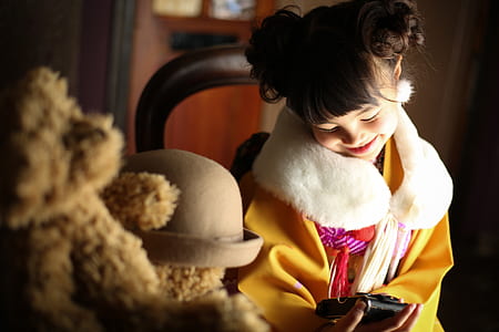 smiling girl sitting on chair holding smartphone during daytime thumbnail