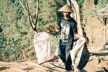 man carrying two straw sacks thumbnail