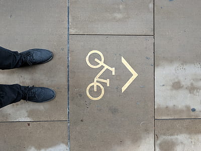 man standing in front of road bicycle signage during daytime thumbnail