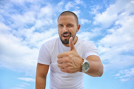 man wearing white shirt doing thumbs up under cumulus clouds thumbnail