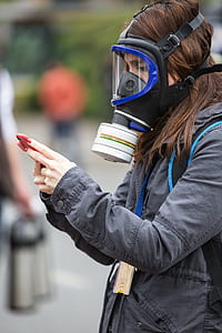 woman wearing gas mask and gray jacket at daytime thumbnail