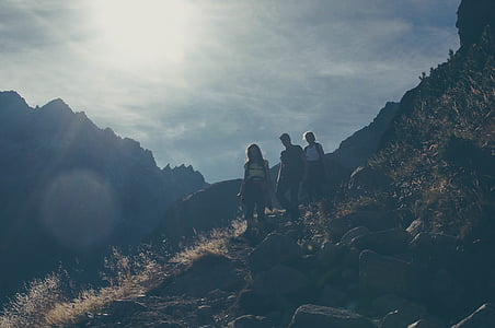 three people walking down on mountain during daytime thumbnail