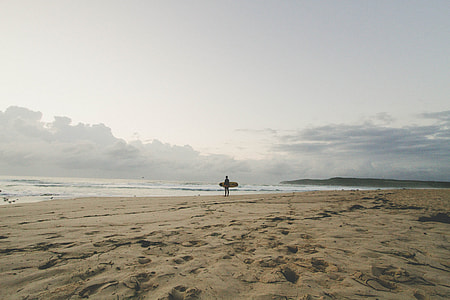 man holding surfboard standing on shoreline thumbnail