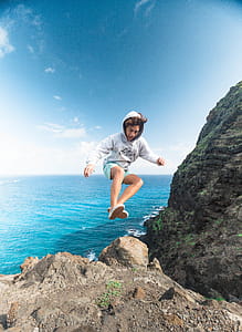 Man Wearing Gray Hoodie Jumping at Rock thumbnail