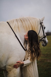 woman kissing a horse during daytime thumbnail
