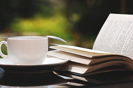 focus photography of white ceramic teacup next to book thumbnail