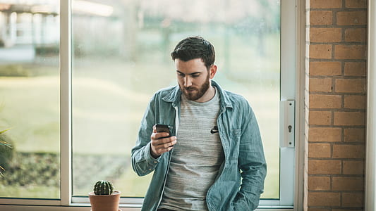 man wearing gray button-up shirt holding smartphone thumbnail